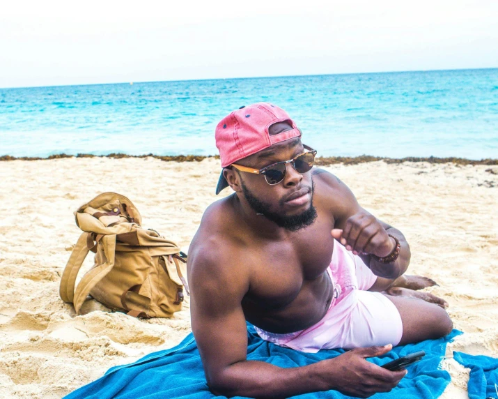 a man sitting on a towel on a beach, by Robbie Trevino, pexels contest winner, happening, brown skin, doomfist from overwatch, kevin hart, vacation photo