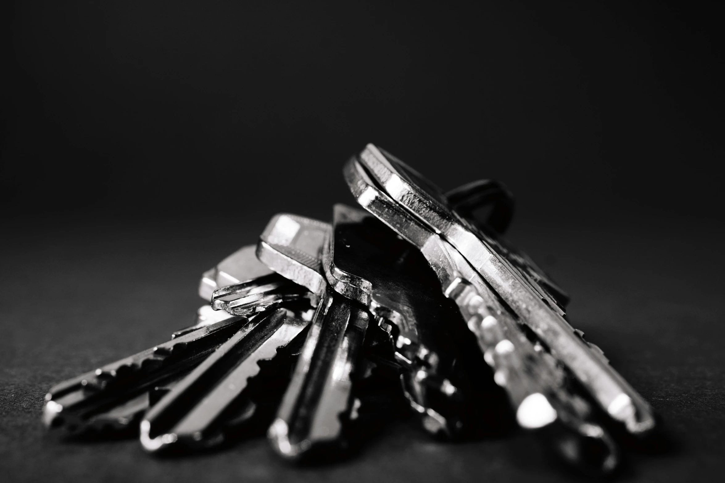 a bunch of keys sitting on top of a table, a black and white photo, by Karl Buesgen, pexels, metal handles, black background, polished, hexagonal shaped
