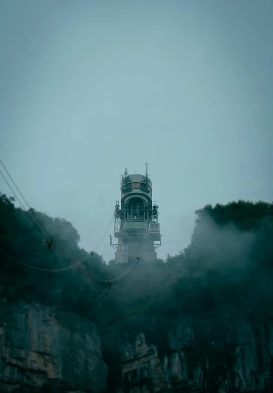 a tall tower sitting on top of a lush green hillside, a matte painting, unsplash, romanticism, battleship, gloomy misty atmosphere, search lights, cinestill hasselblad 2 0 0 mm