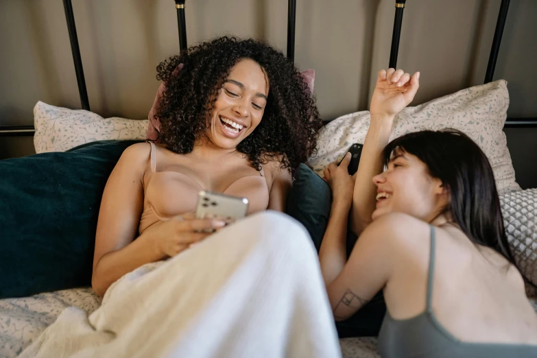 a couple of women sitting on top of a bed, trending on pexels, happening, both laughing, phone photo, bralette, casual game