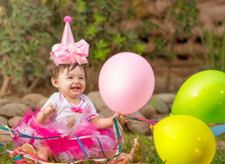 a little girl that is sitting in the grass with balloons, a portrait, pexels, wearing a pink head band, happy birthday, ameera al taweel, bows