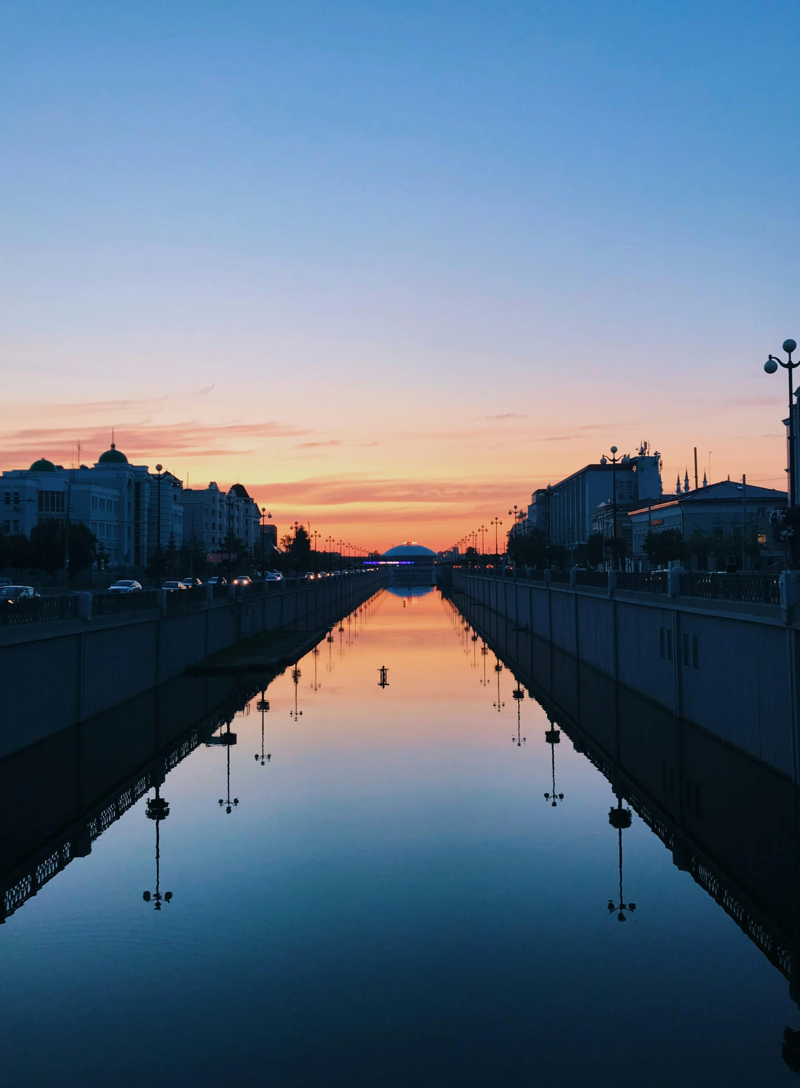 a canal in the middle of a city at sunset, a picture, pexels contest winner, socialist realism, symmetrical image, khreschatyk, high quality print, album cover