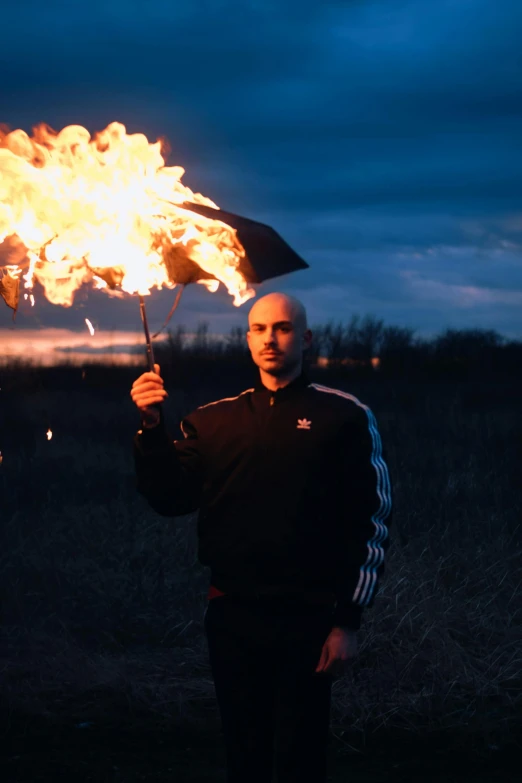 a man holding an umbrella with fire coming out of it, an album cover, by Adam Marczyński, pexels contest winner, bald man, man in adidas tracksuit, instagram picture, profile picture