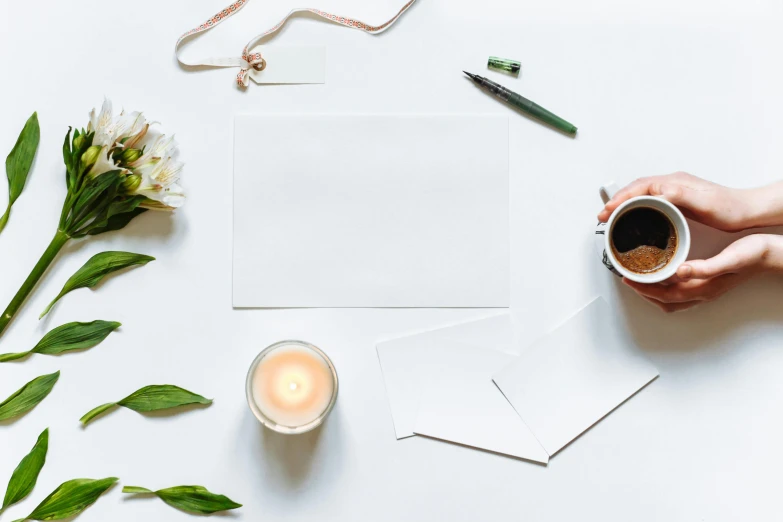 a person holding a cup of coffee on top of a table, a still life, pexels contest winner, private press, smokey burnt love letters, white space in middle, white candles, pen on white paper