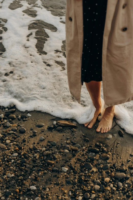 a woman standing on top of a beach next to the ocean, unsplash, renaissance, wet feet in water, wears a long robe, real human feet, rippling