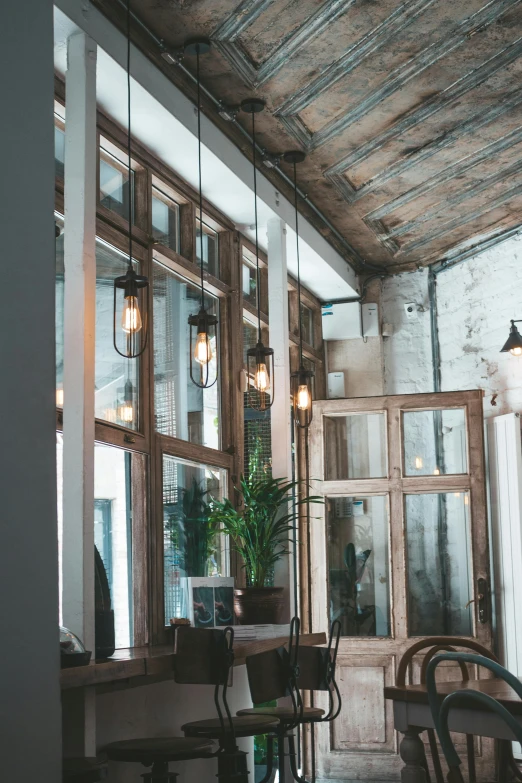 a room filled with lots of tables and chairs, a portrait, by Adriaen Hanneman, unsplash, hanging lanterns, rustic wood, tall windows, recessed