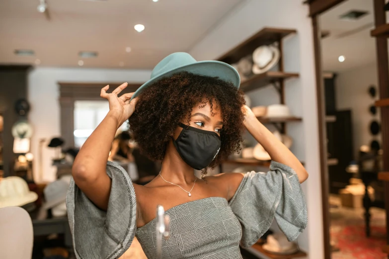 a woman wearing a face mask and a hat, trending on pexels, happening, afro hair, put on a mannequin, thumbnail, elegantly dressed