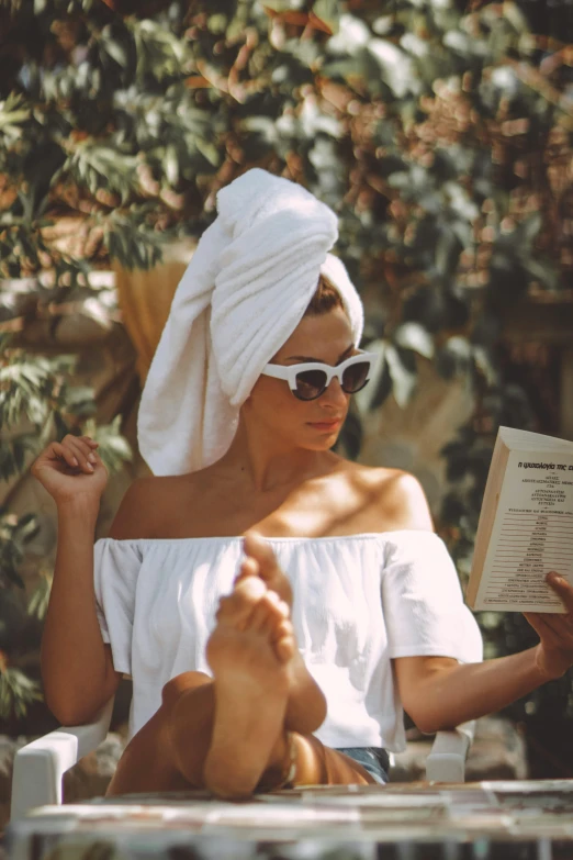 a woman sitting in a chair reading a book, by Julia Pishtar, pexels contest winner, renaissance, wearing a towel, shades, wearing white dress, skincare