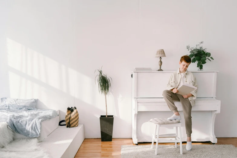 a man sitting on a stool in front of a piano, trending on pexels, light and space, white color scheme, small and cosy student bedroom, owen klatte, some people are sitting