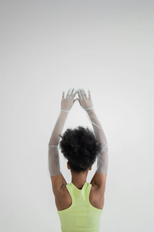 a woman doing a yoga pose with her hands in the air, an album cover, by Lily Delissa Joseph, pexels, afrofuturism, white bandage tape on fists, view from back, translucent, made of plastic