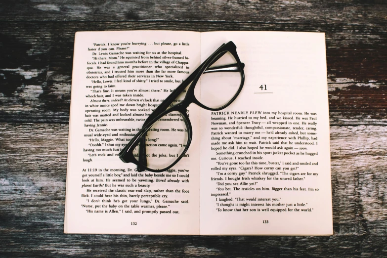 an open book with a pair of glasses on top of it, by Carey Morris, unsplash, square rimmed glasses, a wooden, a single