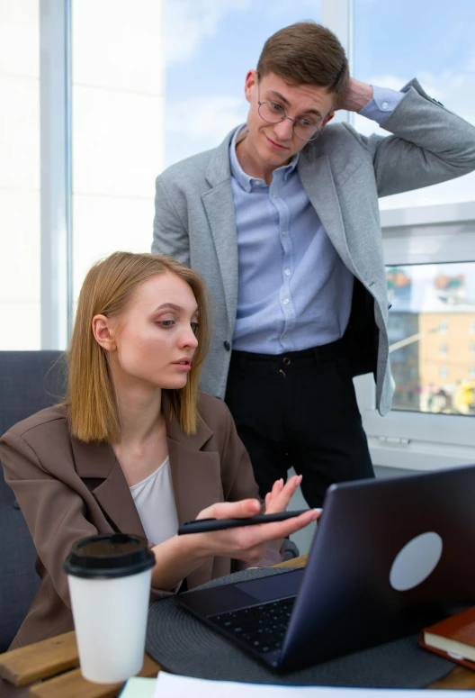 a couple of people sitting at a table with a laptop, in front of a computer, woman in business suit, looking confused, 2019 trending photo