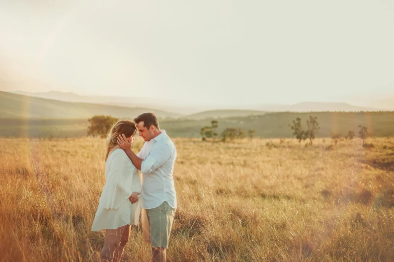 a man and a woman standing in a field, pexels contest winner, maternity feeling, hills in the background, grassy plains, soft glow