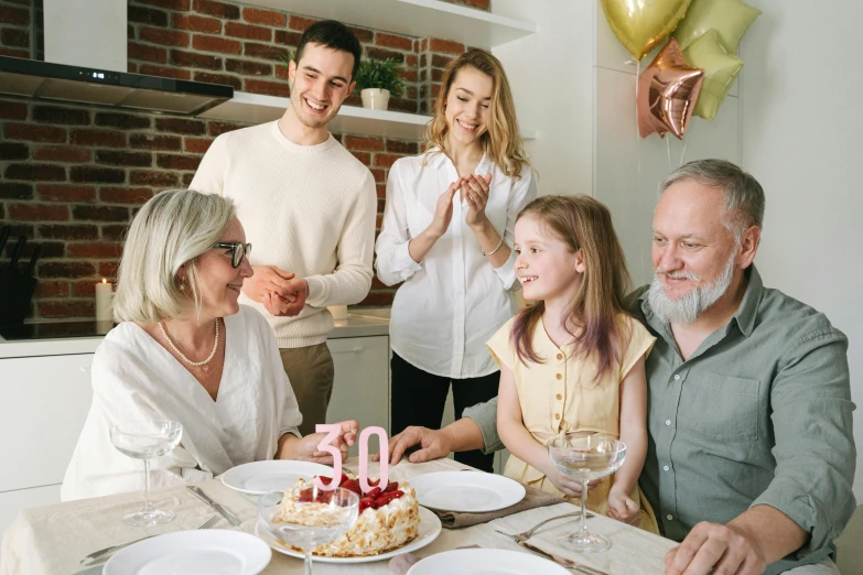 a group of people sitting around a table with a cake, family friendly, -step 50, profile image, gold