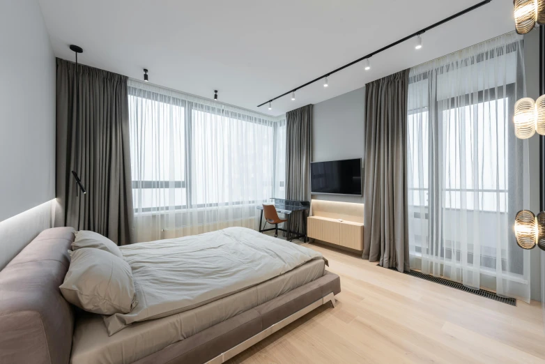 a bed room with a neatly made bed and a flat screen tv, by Adam Marczyński, unsplash, light and space, floor - to - ceiling windows, drapery, 000 — википедия, oak