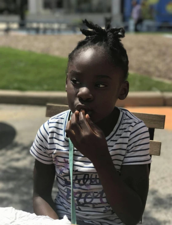 a little girl sitting at a table eating a donut, dark skinned, smoking outside, trending photo, 🤤 girl portrait