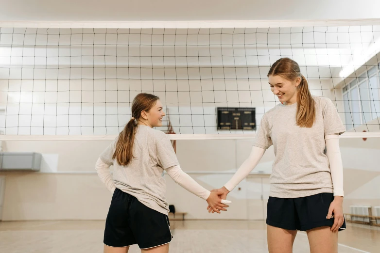 two girls shaking hands on a volleyball court, by Emma Andijewska, pexels contest winner, renaissance, indoor picture, background image, profile pic, thumbnail