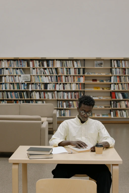 a man sitting at a table reading a book in a library, trending on unsplash, adut akech, ignant, completely empty, documentary still