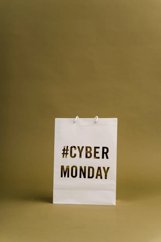 a white paper bag with the word cyber monday written on it, by Julia Pishtar, modernism, hashtags, gold, (1 as december, monaco