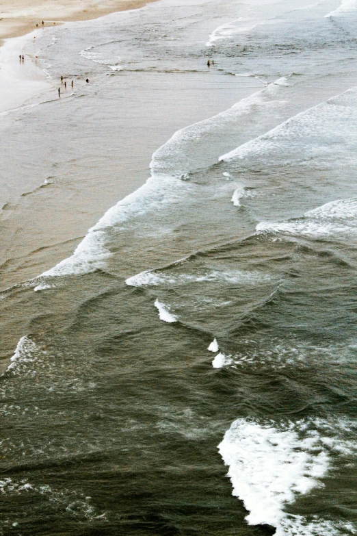 a group of people standing on top of a beach next to the ocean, inspired by Andreas Gursky, renaissance, rushing water, 1999 photograph, close - up photograph, aerial