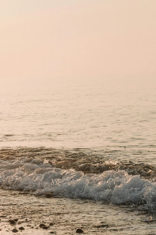 a man riding a surfboard on top of a wave covered beach, inspired by Elsa Bleda, trending on unsplash, romanticism, faded pink, subtle fog, muted brown, view of sea