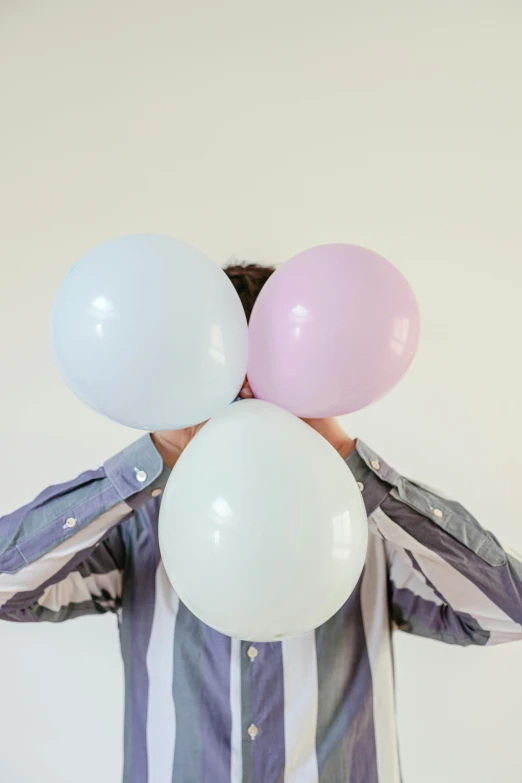 a man holding a bunch of balloons in front of his face, by Nina Hamnett, trending on unsplash, pale pastel colours, white sleeves, party, blank