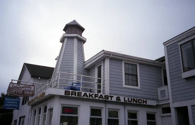 a white building with a clock tower on top of it, a colorized photo, by David Brewster, unsplash, photorealism, hearty breakfast, shoreline, ca. 1990, photo taken on fujifilm superia