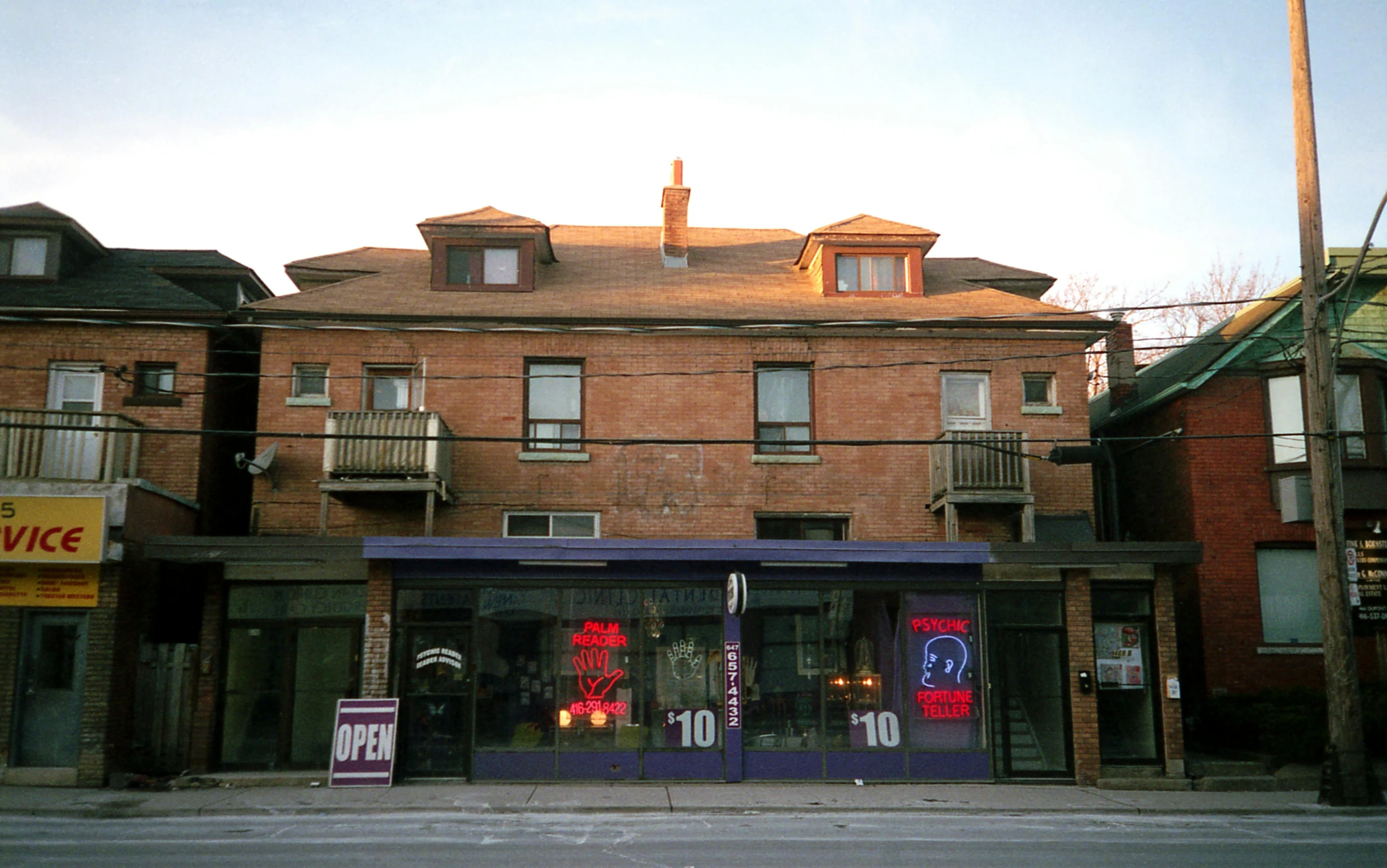 a tall brick building sitting on the side of a street, brightly lit purple room, the store, ten flats, toronto