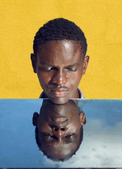 a man sitting in front of a laptop computer, an album cover, inspired by David Bailly, pexels contest winner, dada, half face in the water, ( ( brown skin ) ), yellow pupils, mirrored