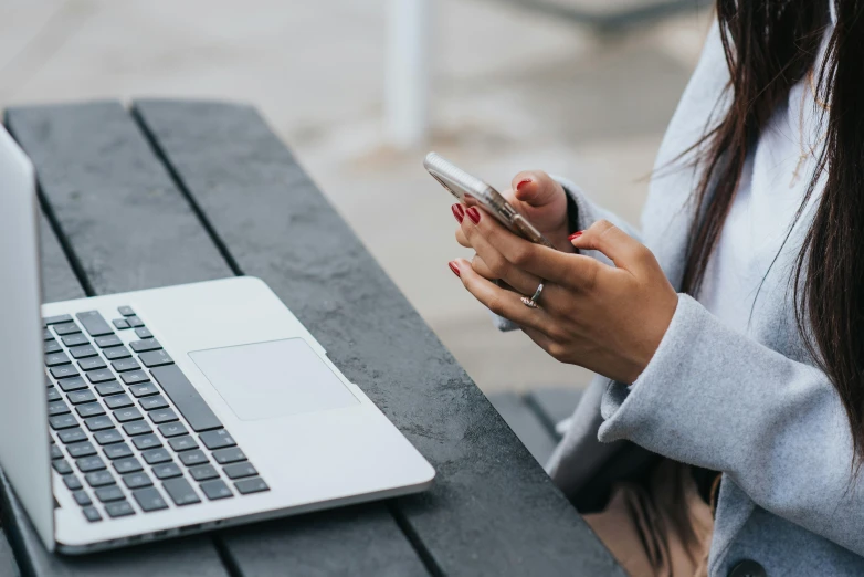 a woman sitting at a table with a laptop and cell phone, trending on pexels, avatar image, close up photo, background image, 1 2 9 7