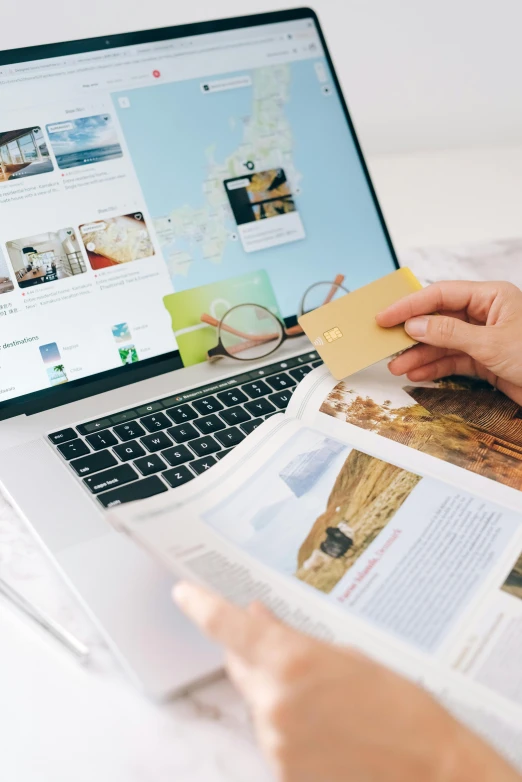 a person holding a piece of paper in front of a laptop, travel guide, thumbnail, gold, ecommerce photograph