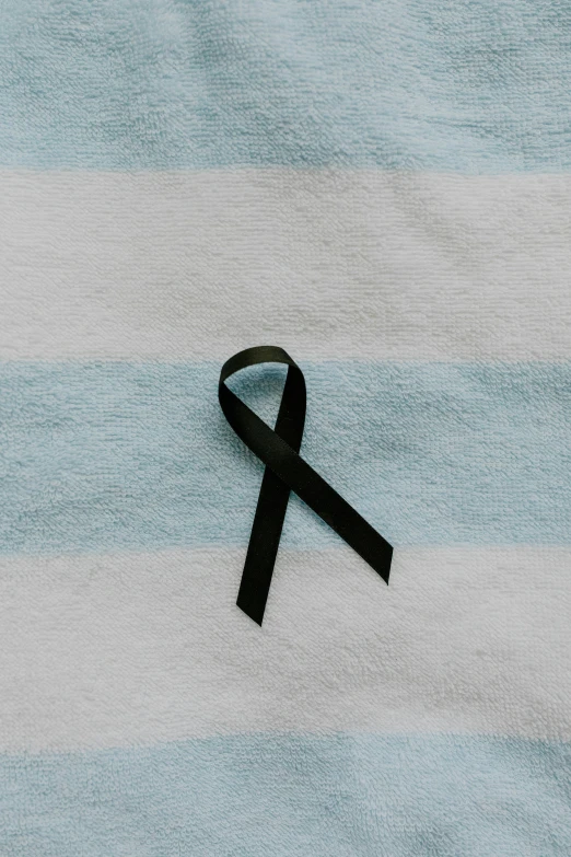 a black ribbon laying on top of a blue and white towel, by Nina Hamnett, unsplash, instagram post, disease, remembrance, profile pic