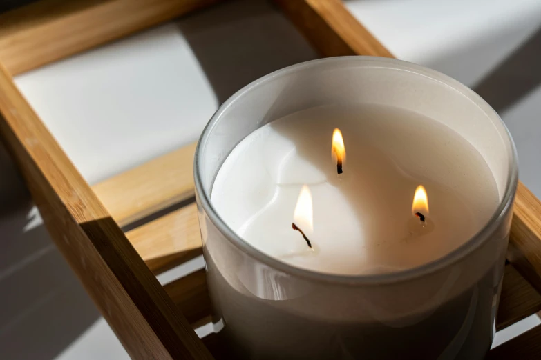 a candle sitting on top of a wooden box, unsplash, glossy white, close up angle, light grey mist, on a wooden tray