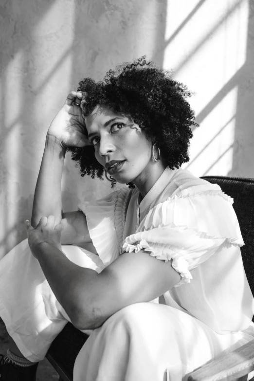 a black and white photo of a woman sitting on a couch, inspired by Carrie Mae Weems, renaissance, imaan hammam, with a curly perm, a beautiful woman in white, square