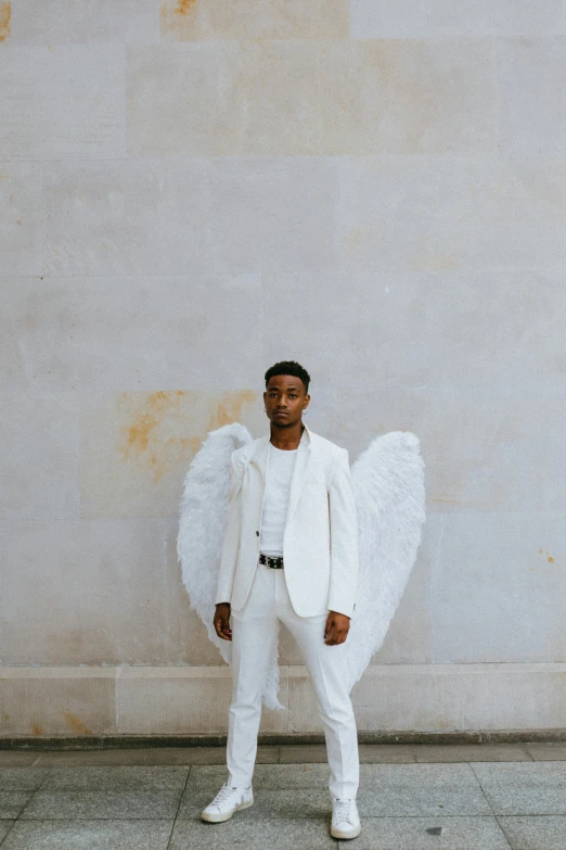 a man in a white suit standing in front of a wall, inspired by Louis Hersent, pexels contest winner, renaissance, young wan angel, playboi carti, wide open wings, cupid