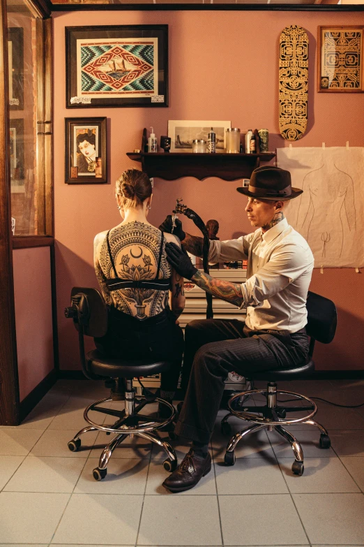 a couple of men sitting at a desk in a room, a tattoo, by Sam Black, pexels contest winner, art nouveau, panoramic shot, tattoo parlor photo, profile image
