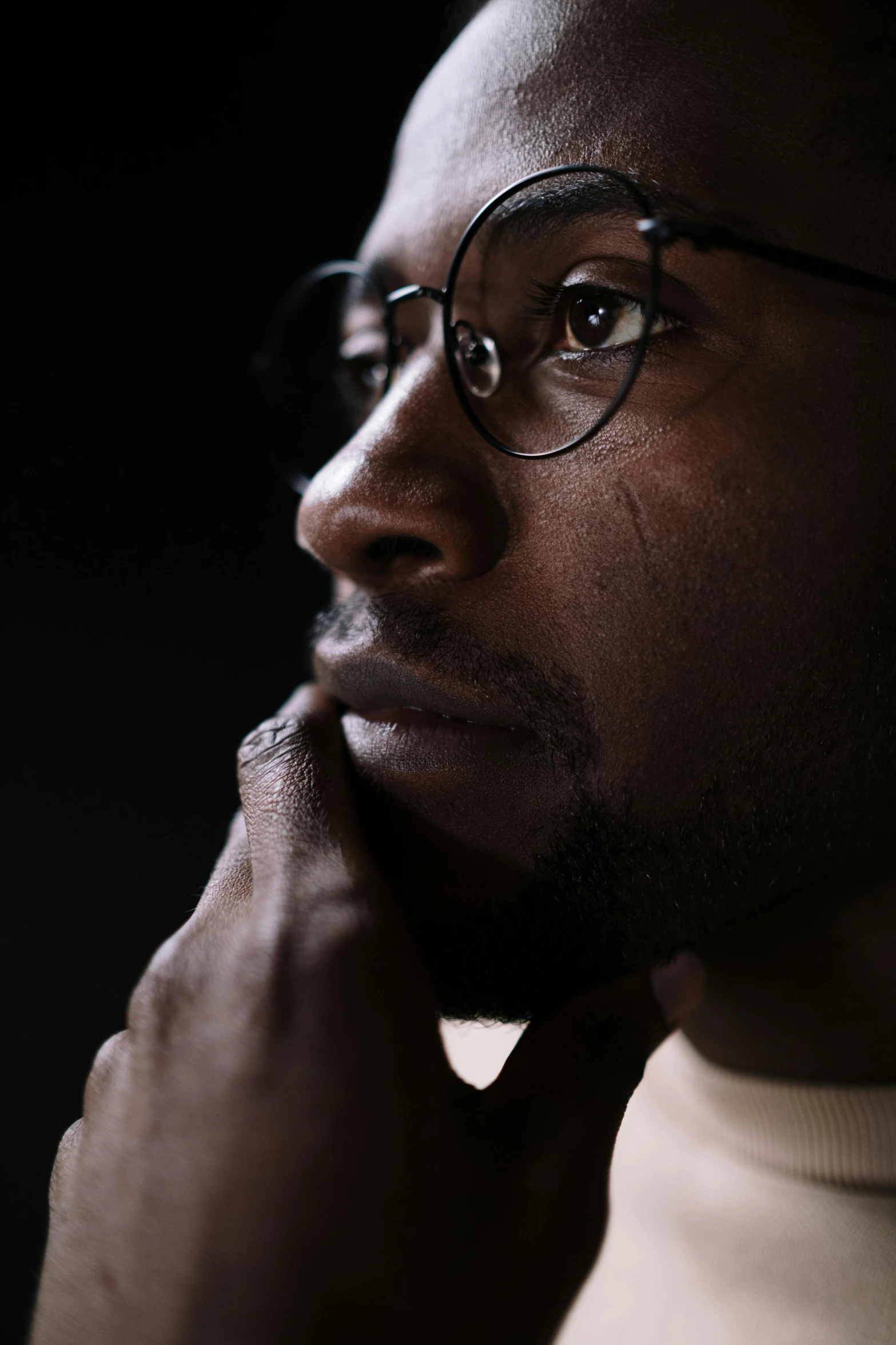 a close up of a person wearing glasses, a character portrait, inspired by Ibram Lassaw, pexels, hyperrealism, man sitting facing away, dark skinned, slide show, pondering