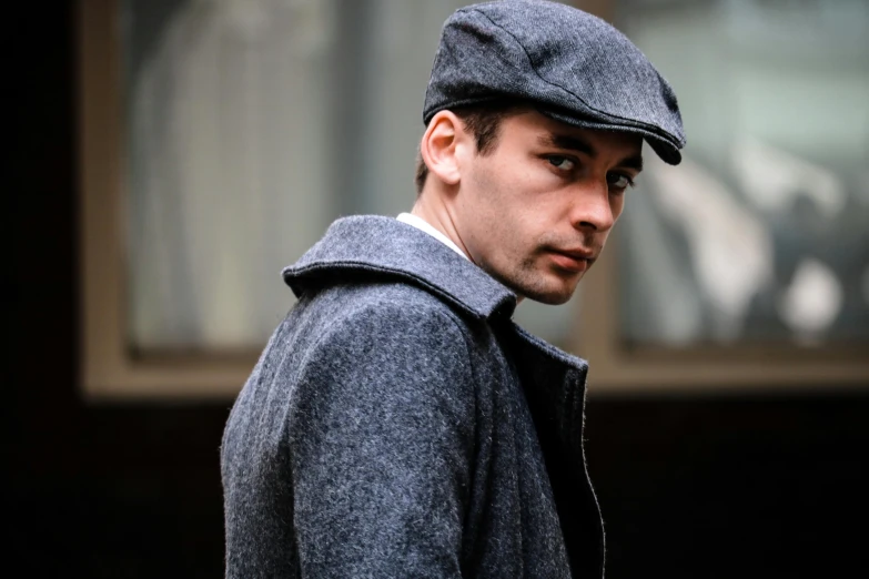 a close up of a person wearing a hat, inspired by Max Magnus Norman, reddit, in gunmetal grey, newsboy cap, charlie cox, tailored clothing