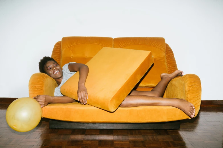 a woman laying on a couch with a pillow on it, inspired by Sarah Lucas, pexels contest winner, anthropomorphic cheese wedge, african american young woman, ocher, excitement