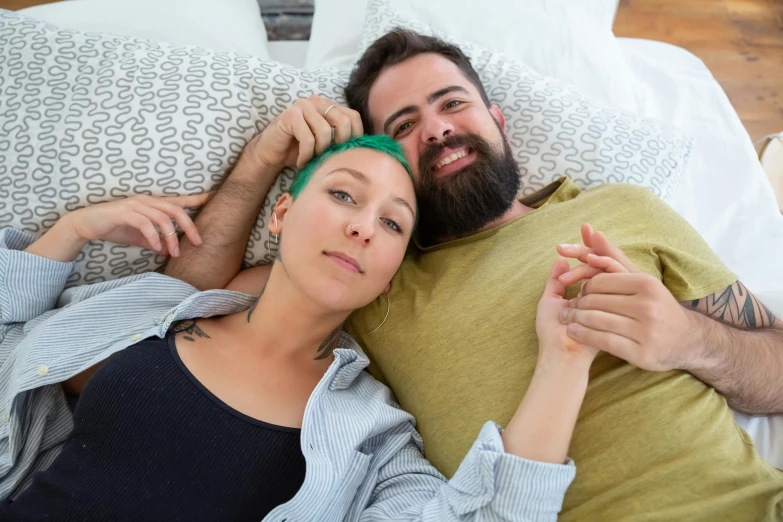 a man and a woman laying on a bed, pexels contest winner, short green hair, beard, supportive, nursing