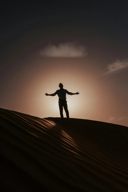 a man standing on top of a sand dune, pexels contest winner, symbolism, outlined silhouettes, arms open, oman, beautifully lit