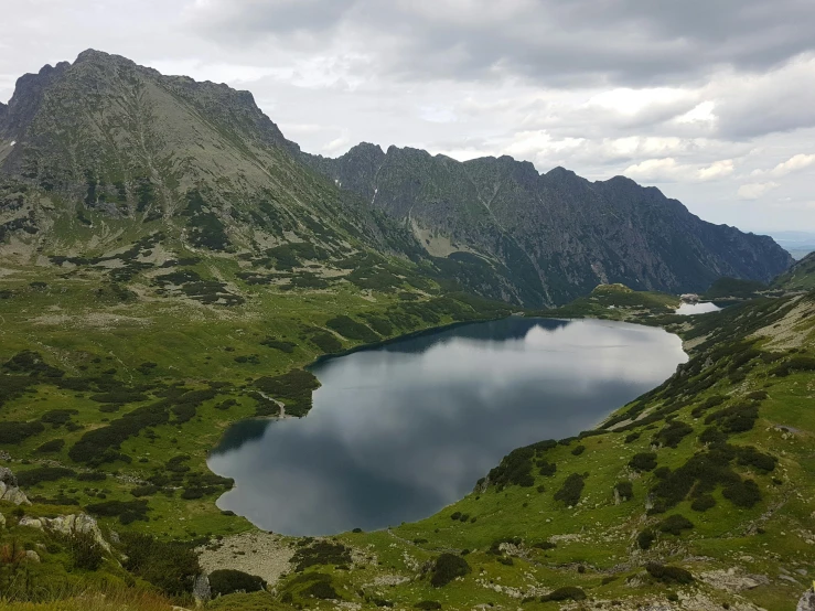 a large body of water sitting on top of a lush green hillside, by Emma Andijewska, pexels contest winner, hurufiyya, integrated in the mountains, warsaw, фото девушка курит, crystal lake