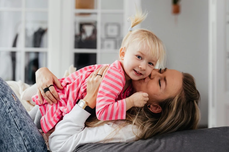 a woman laying on top of a couch holding a little girl, pexels contest winner, manuka, profile image, hugging, extremely high resolution