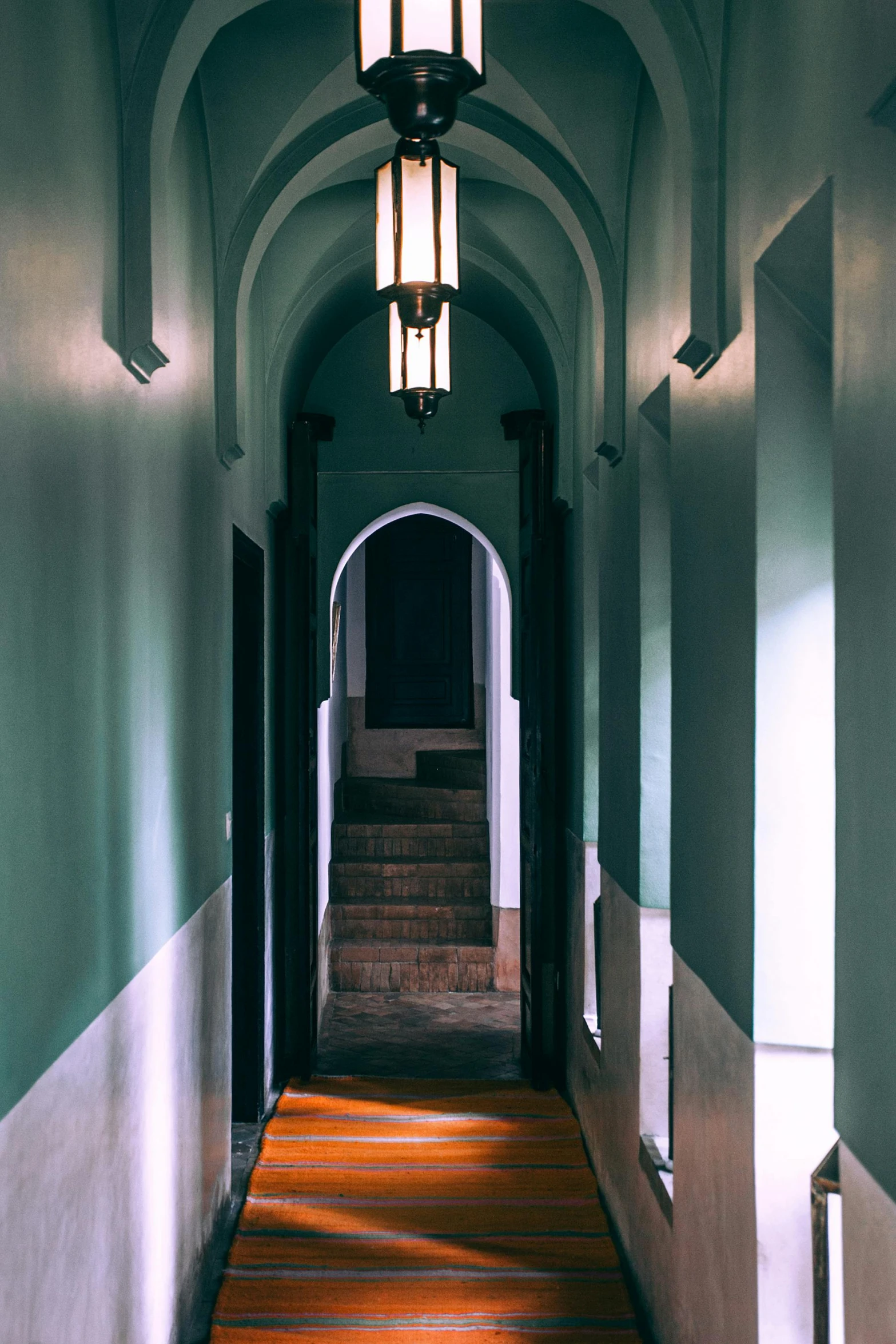 a long hallway with a light hanging from the ceiling, inspired by Luis Paret y Alcazar, unsplash, glowing hue of teal, colonial style, arch, up there