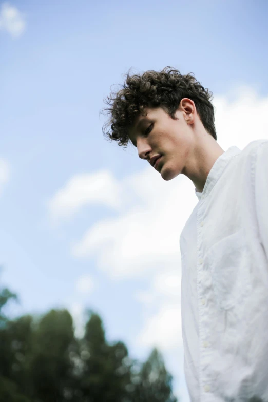 a man standing in a field with a frisbee, an album cover, by Jacob Toorenvliet, trending on unsplash, renaissance, he has short curly brown hair, wearing white clothes, close - up profile face, attractive androgynous humanoid