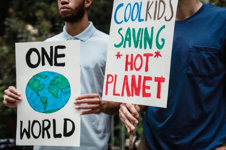 a couple of men standing next to each other holding signs, trending on pexels, living planet, kids, global warming, half image