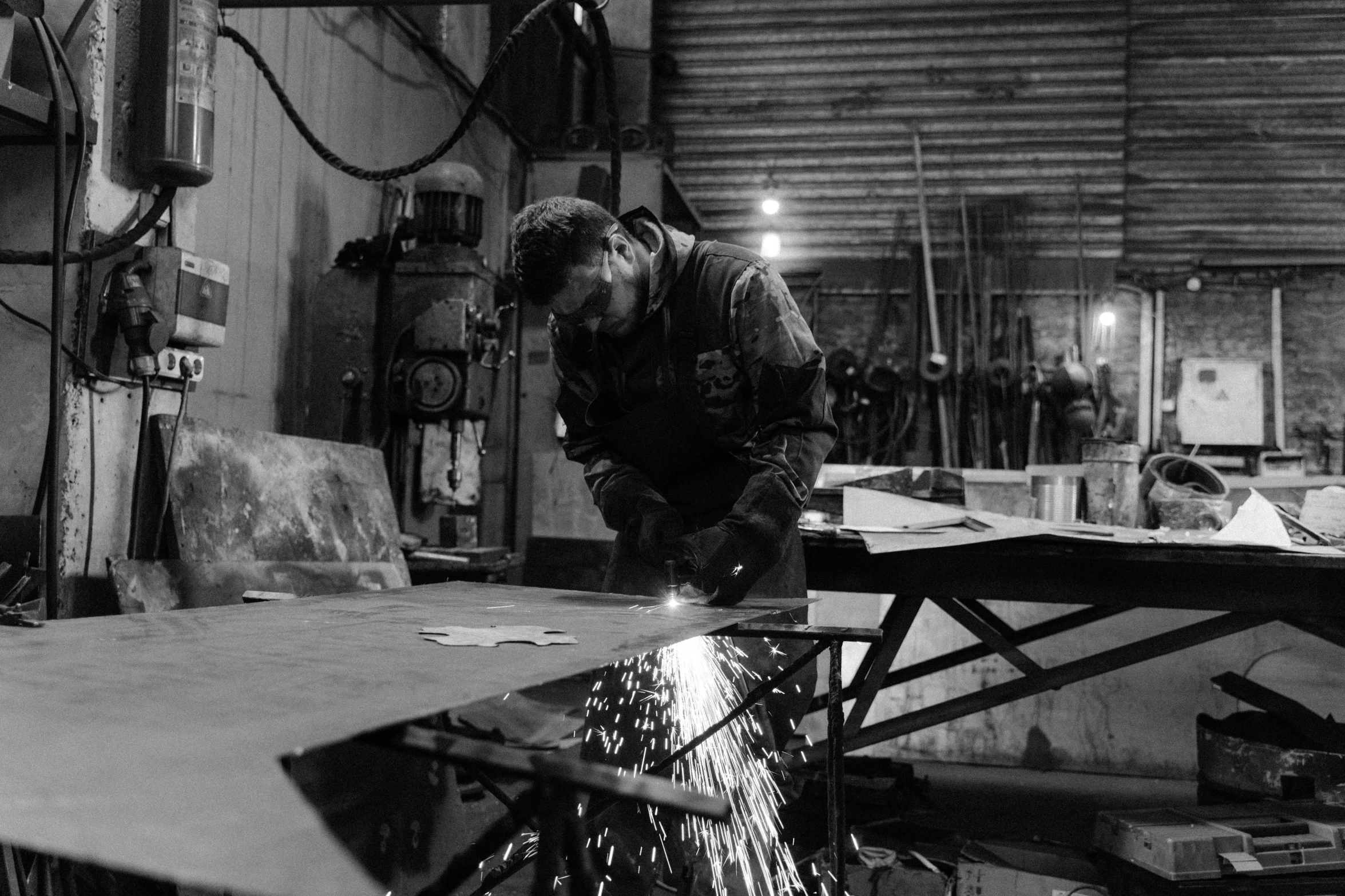 a black and white photo of a man cutting a piece of wood, by William Berra, pexels, arbeitsrat für kunst, welding torches for arms, steel plating, tiffany dover, a large