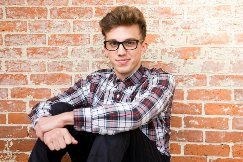 a young man sitting against a brick wall, shutterstock, op art, in square-rimmed glasses, portrait image, matt howarth, teenager