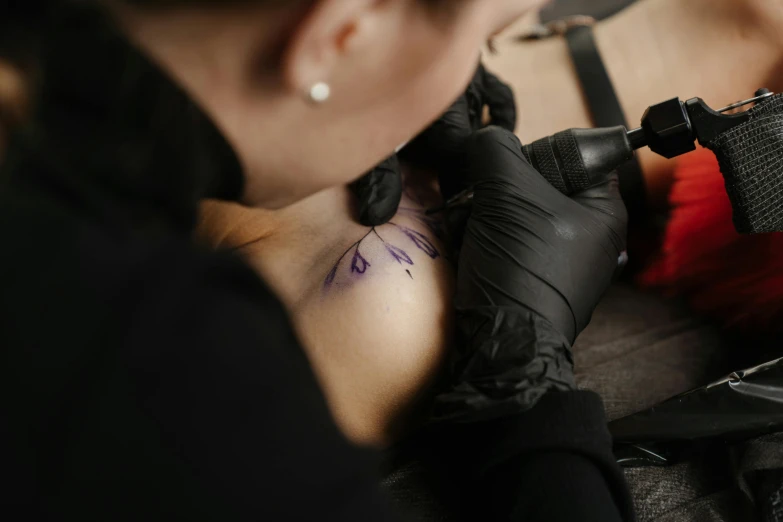 a woman getting a tattoo on her arm, a tattoo, by Adam Marczyński, trending on pexels, black lines, top down photo, 1614572159, colored ink