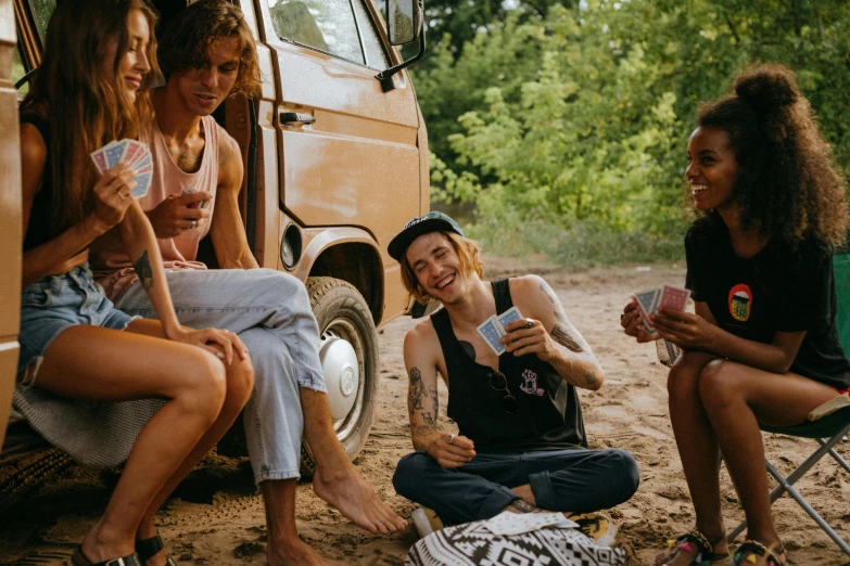 a group of women sitting next to each other in front of a van, pexels contest winner, playing cards, wearing a tank top and shorts, avatar image, wearing dirty travelling clothes